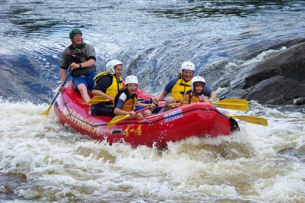 Group of People Laughing While Rafting in a River