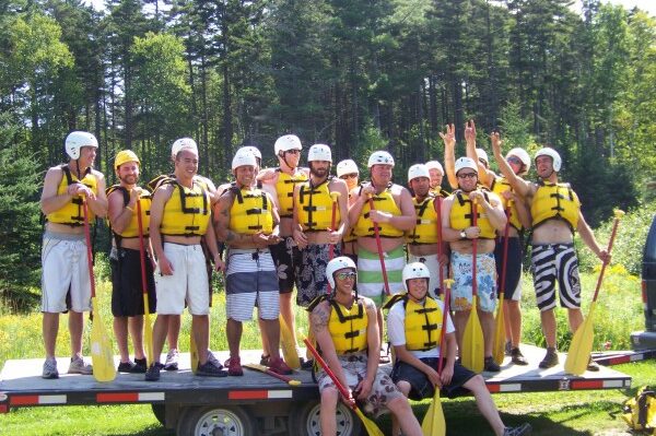 Group of People on a Trailer Smiling With Whitewater Rafting Gear On