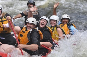 Group of Happy People Waving to the Camera While Whitewater Rafting